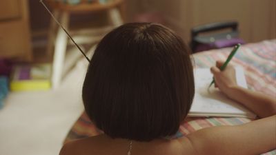 a woman writing in a notebook on a bed