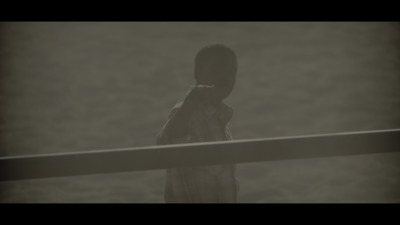 a young boy standing on a beach next to a body of water