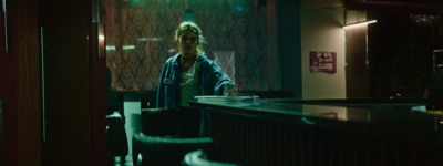 a woman standing at a bar in a dimly lit room