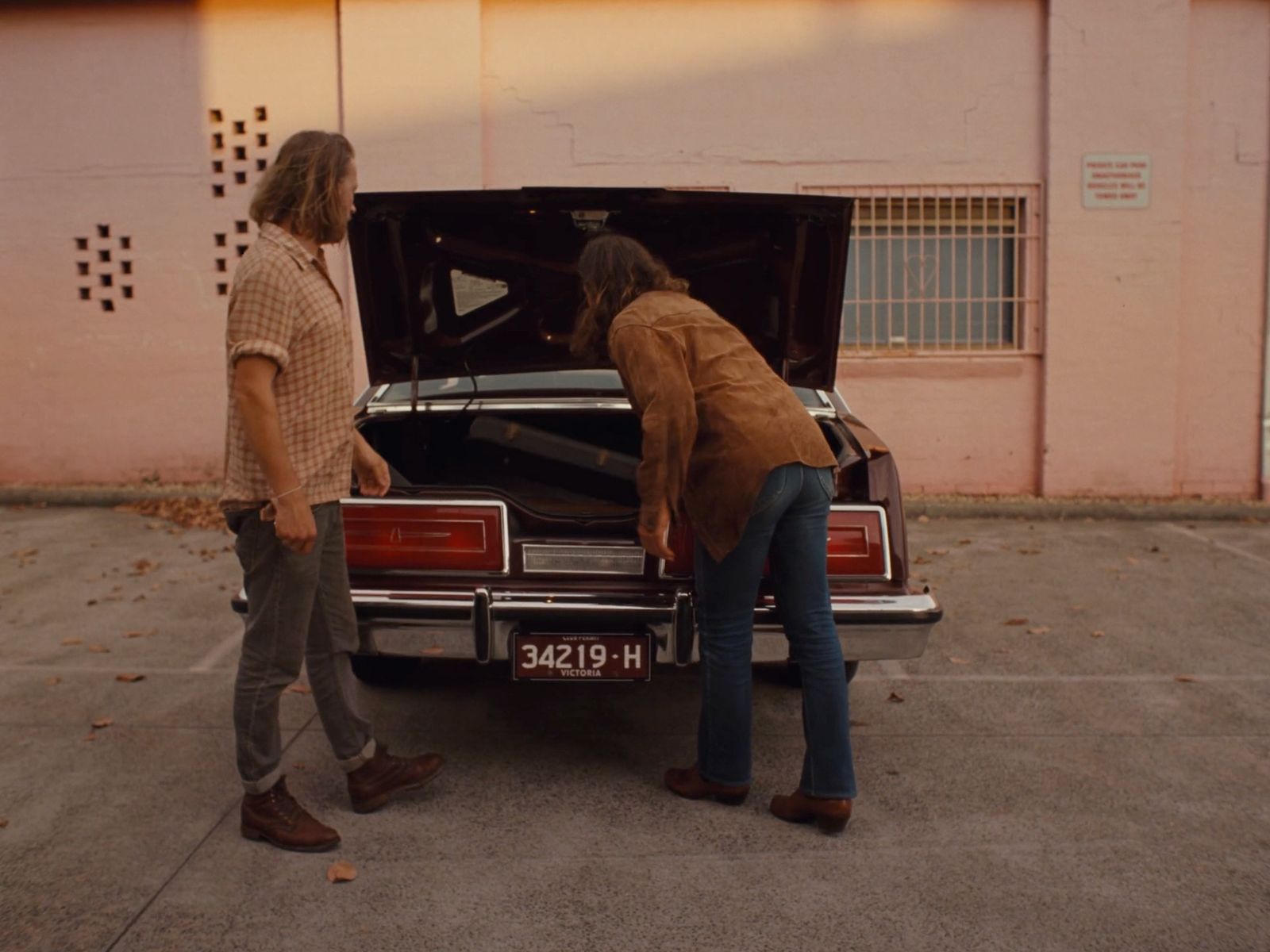 a couple of men standing next to a parked car