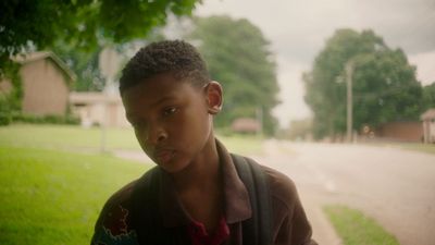 a young boy standing on the side of a road