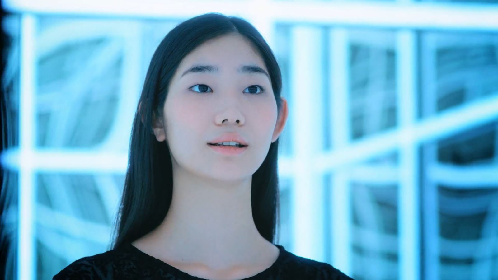 a woman with long black hair standing in front of a window