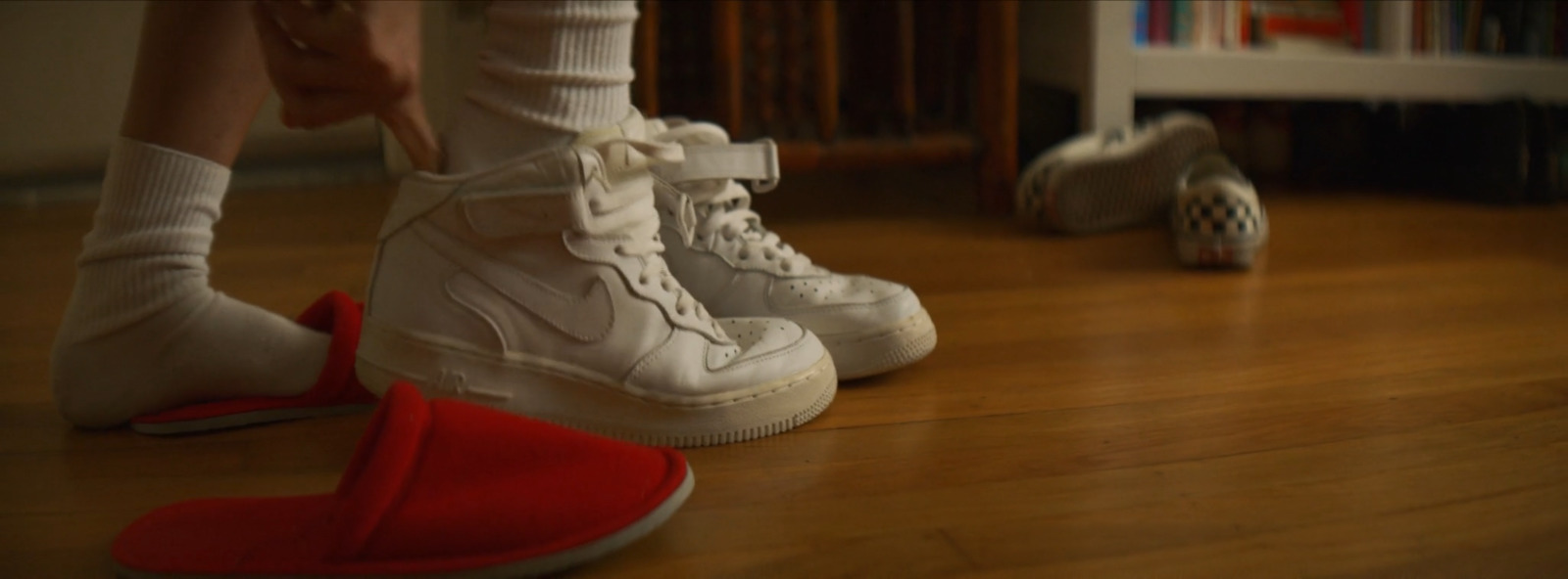 a person standing on a wooden floor next to a pair of shoes