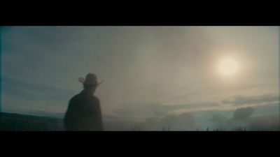 a man wearing a hat standing in a field