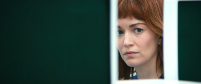 a woman with red hair looking out of a window