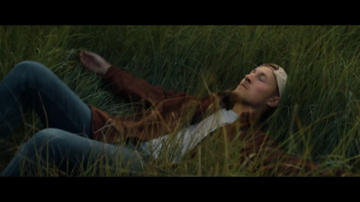 a woman laying in a field of tall grass