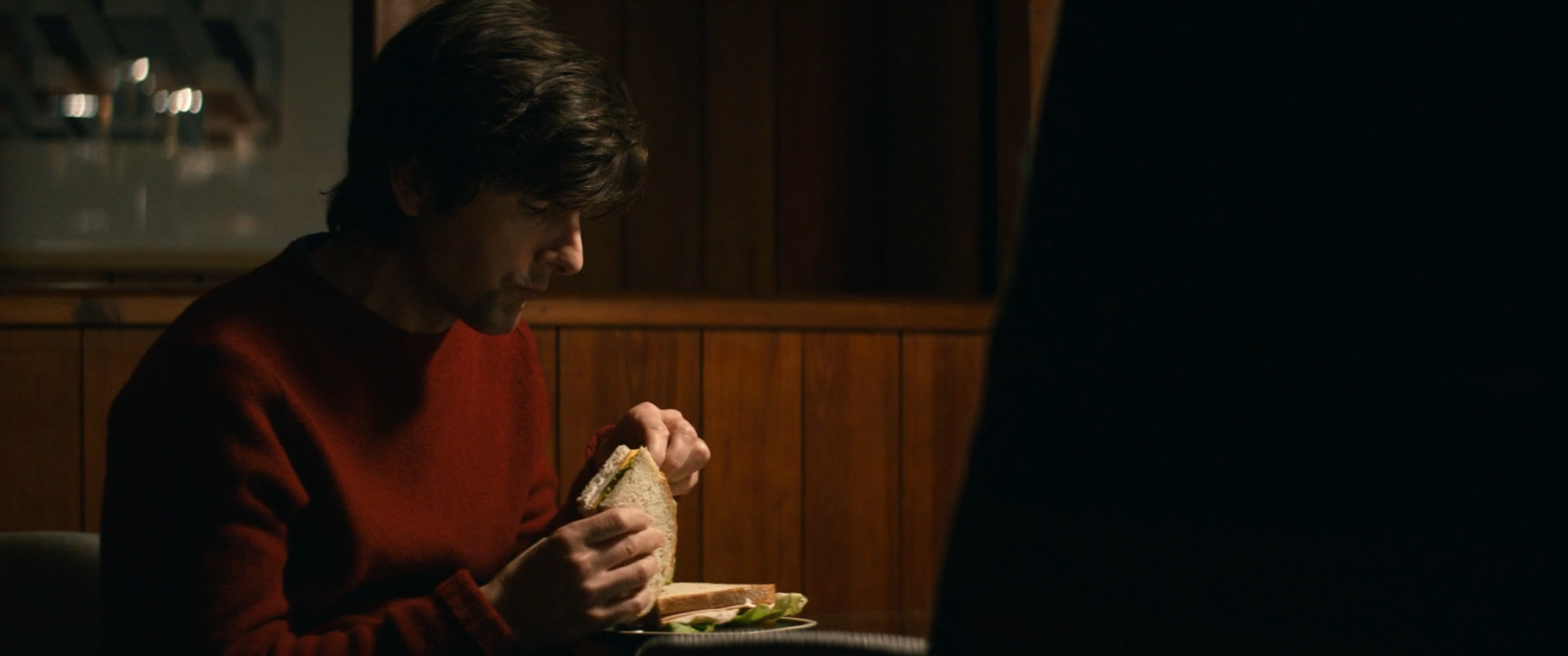 a woman sitting at a table eating a sandwich