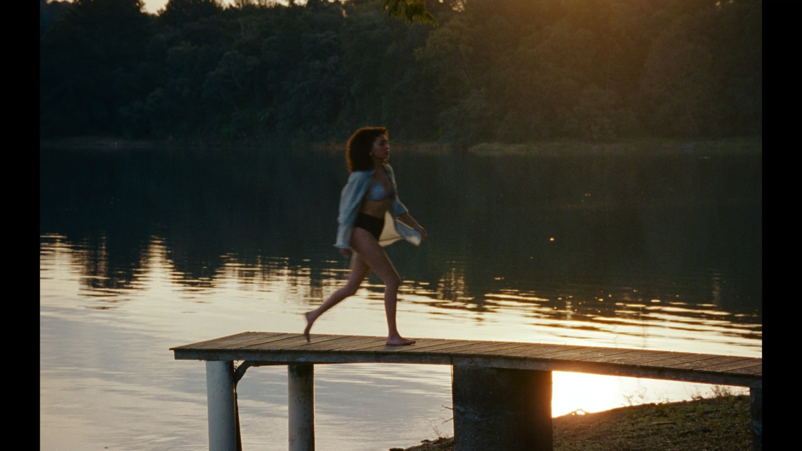 a woman in a bathing suit walking on a dock