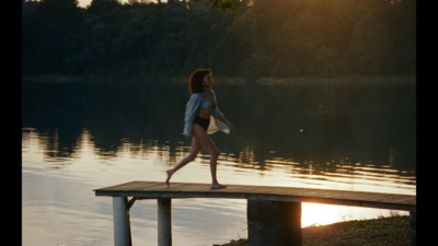 a woman in a bathing suit walking on a dock