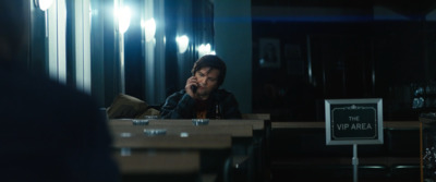 a man sitting at a table talking on a cell phone