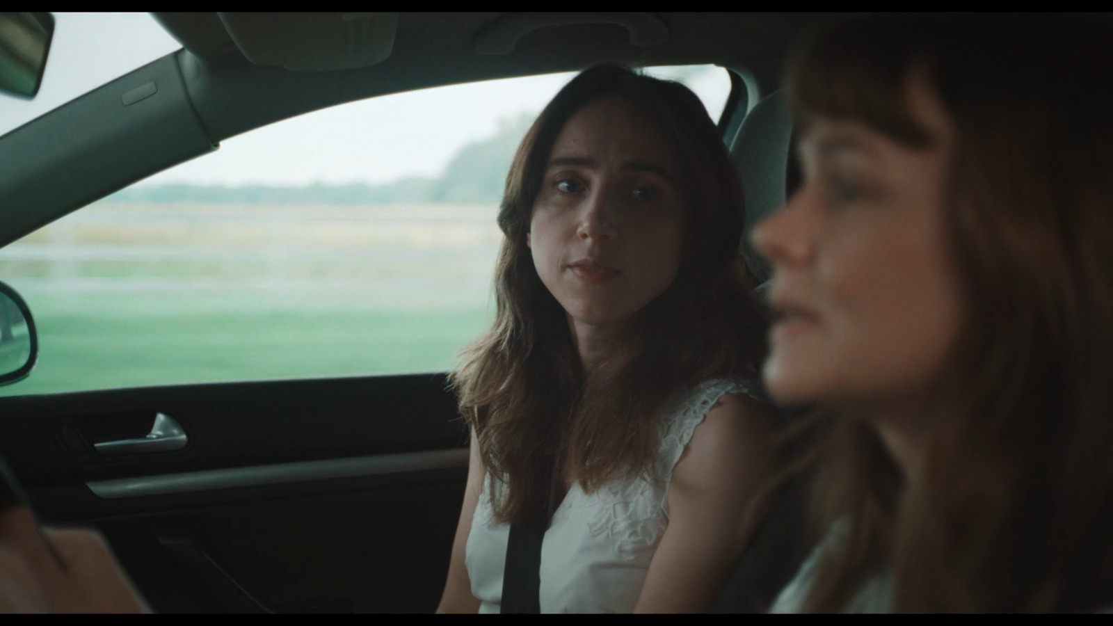 a woman sitting in a car with another woman behind her