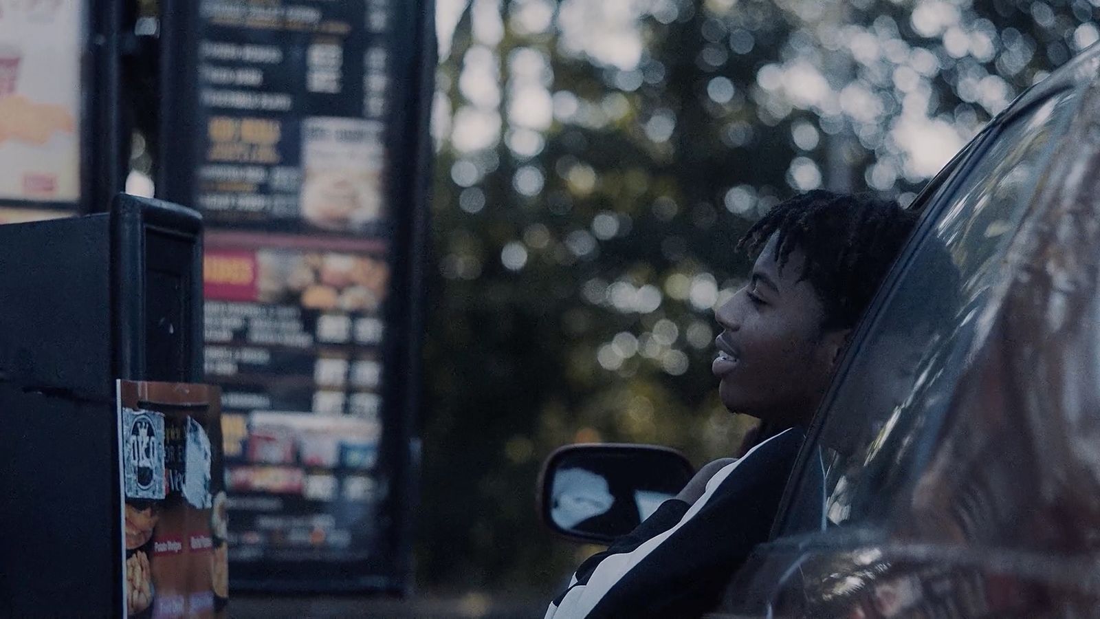 a young man sitting in a car at a fast food restaurant