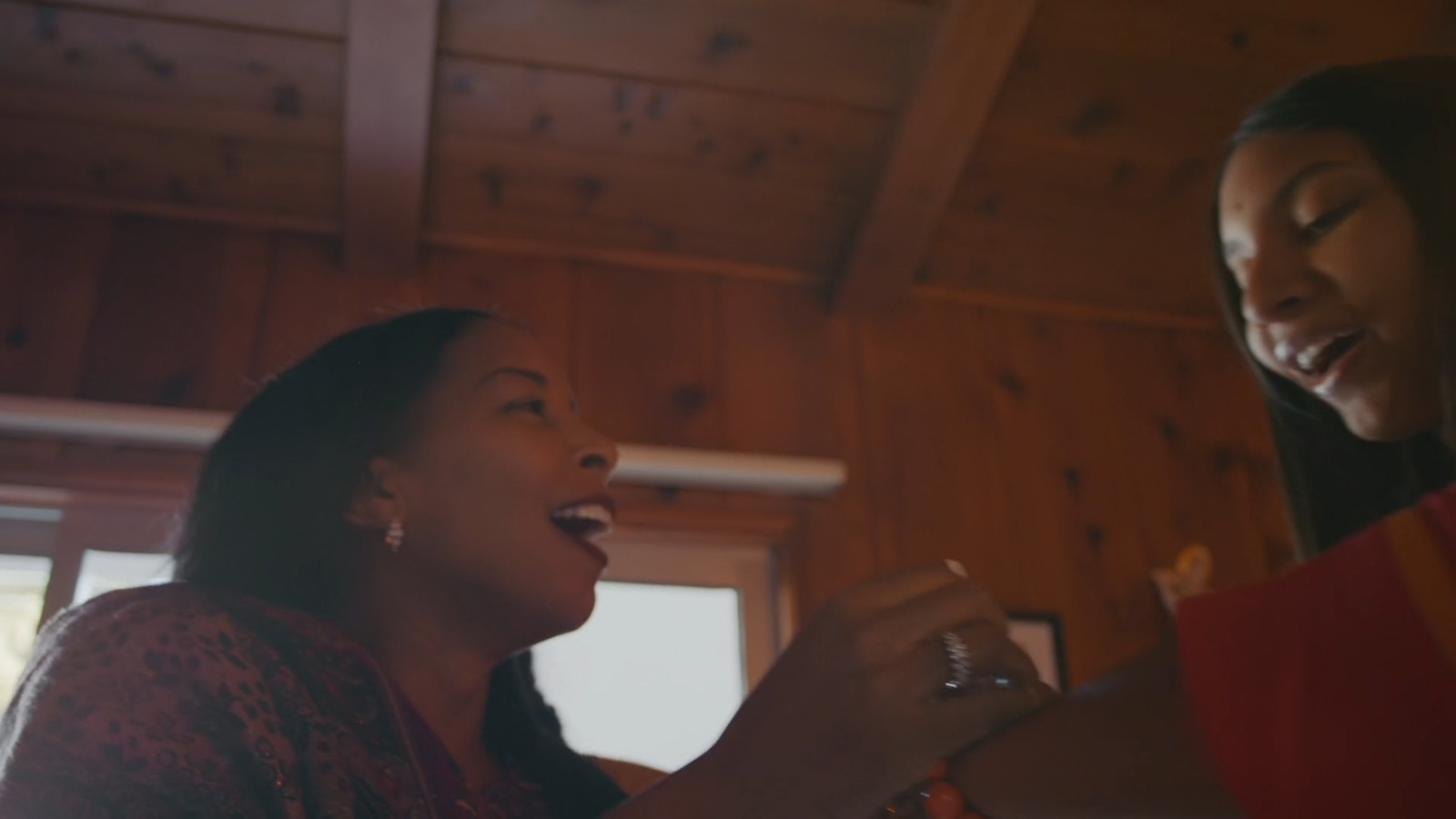 two women are laughing and drinking wine together