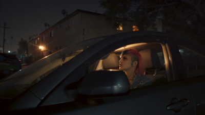 a woman with red hair sitting in a car at night