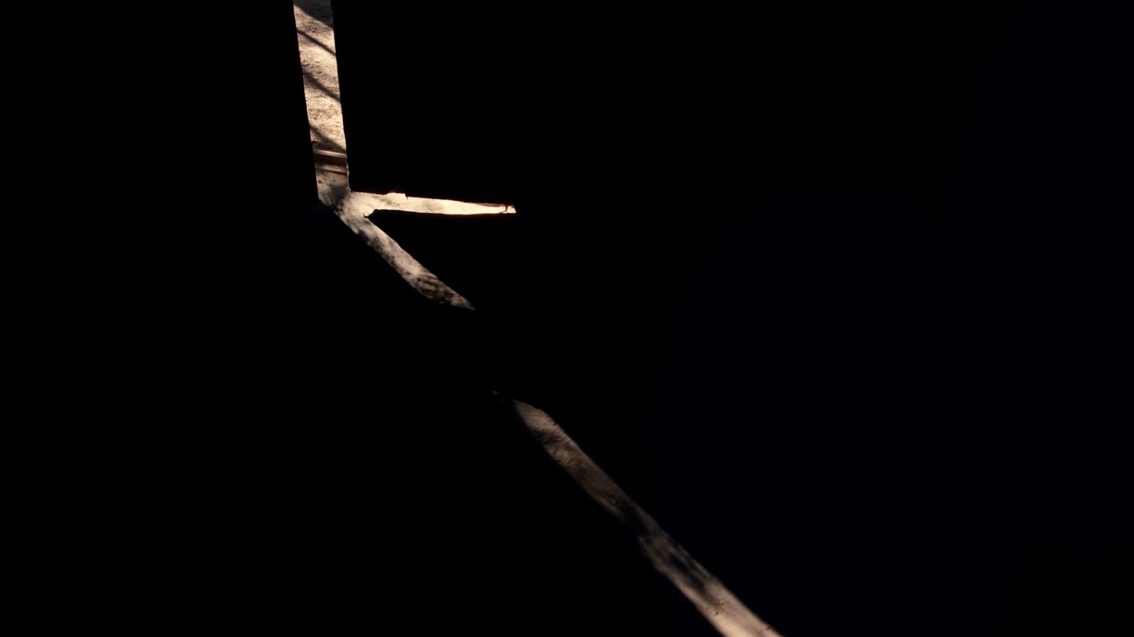 a black and white photo of a cross in the dark