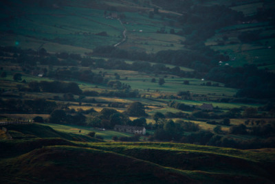 a view of a lush green hillside with a house in the distance