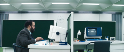 a man sitting at a desk in front of a computer monitor