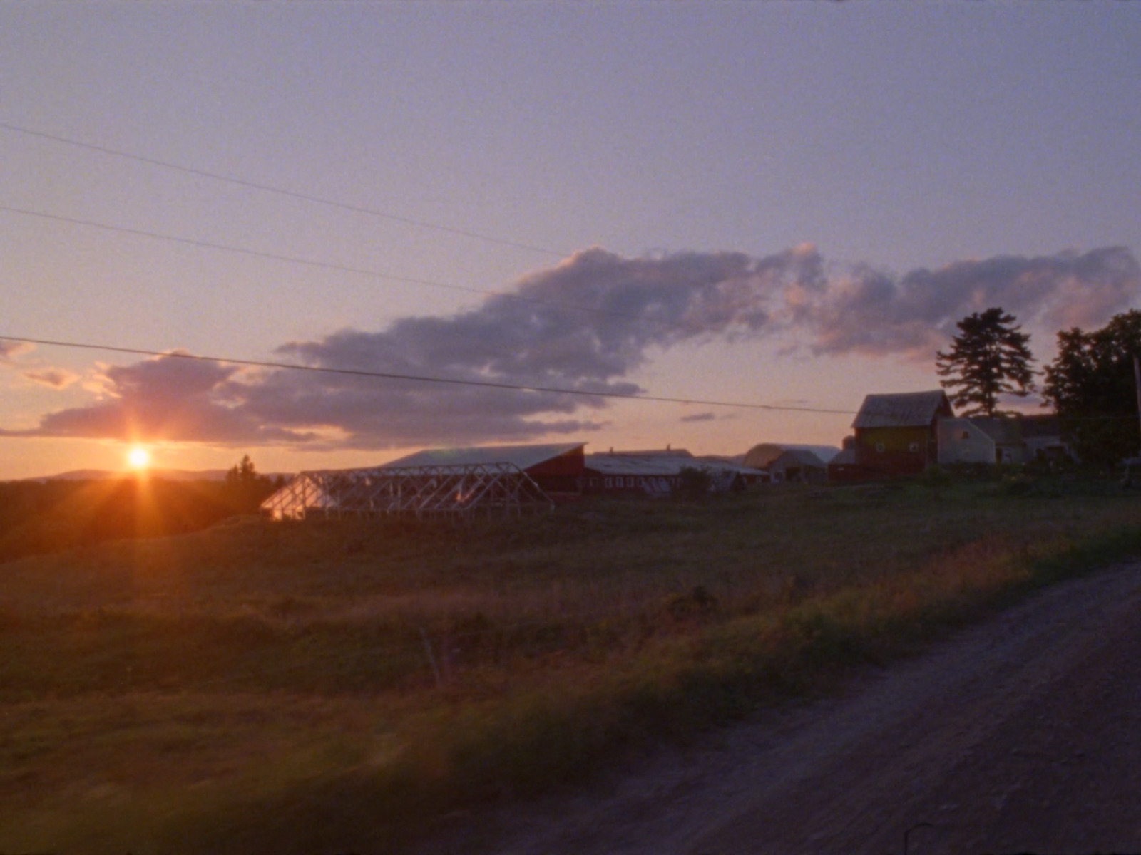 the sun is setting over a farm in the country