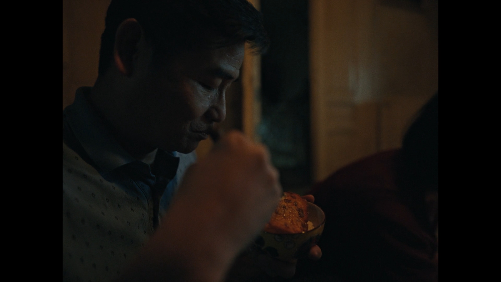 a man eating a bowl of food in a dark room