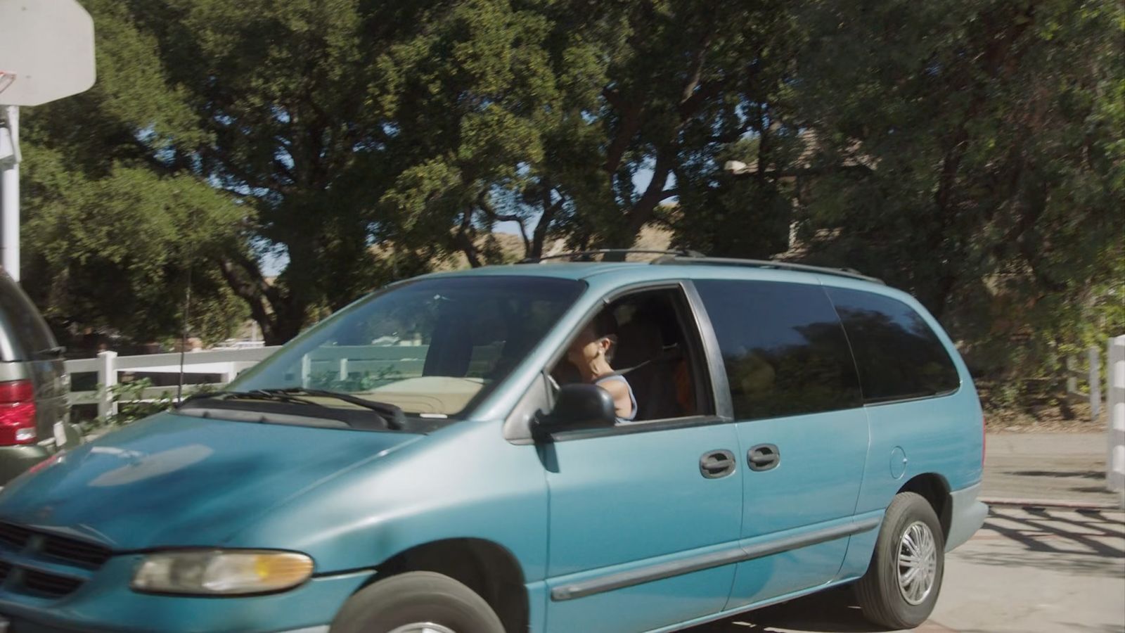 a blue van parked in a parking lot next to a basketball hoop