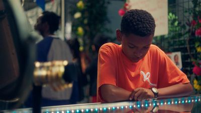 a young boy sitting at a table writing on a piece of paper