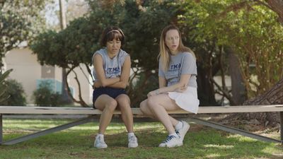 two women sitting on a bench in a park