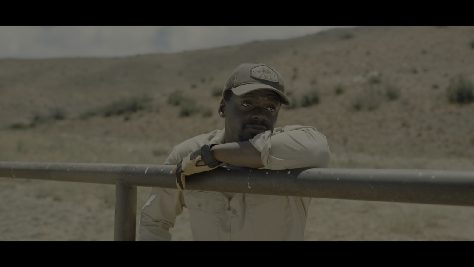 a man leaning on a rail in the desert