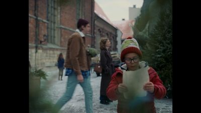 a young boy holding a piece of paper while standing next to a woman