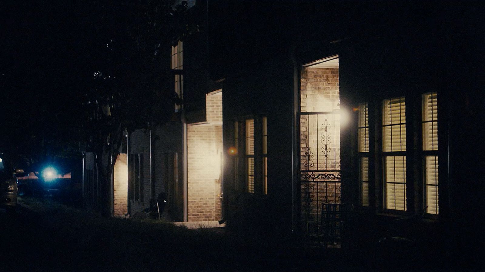 a dark street at night with a car parked on the side of the road