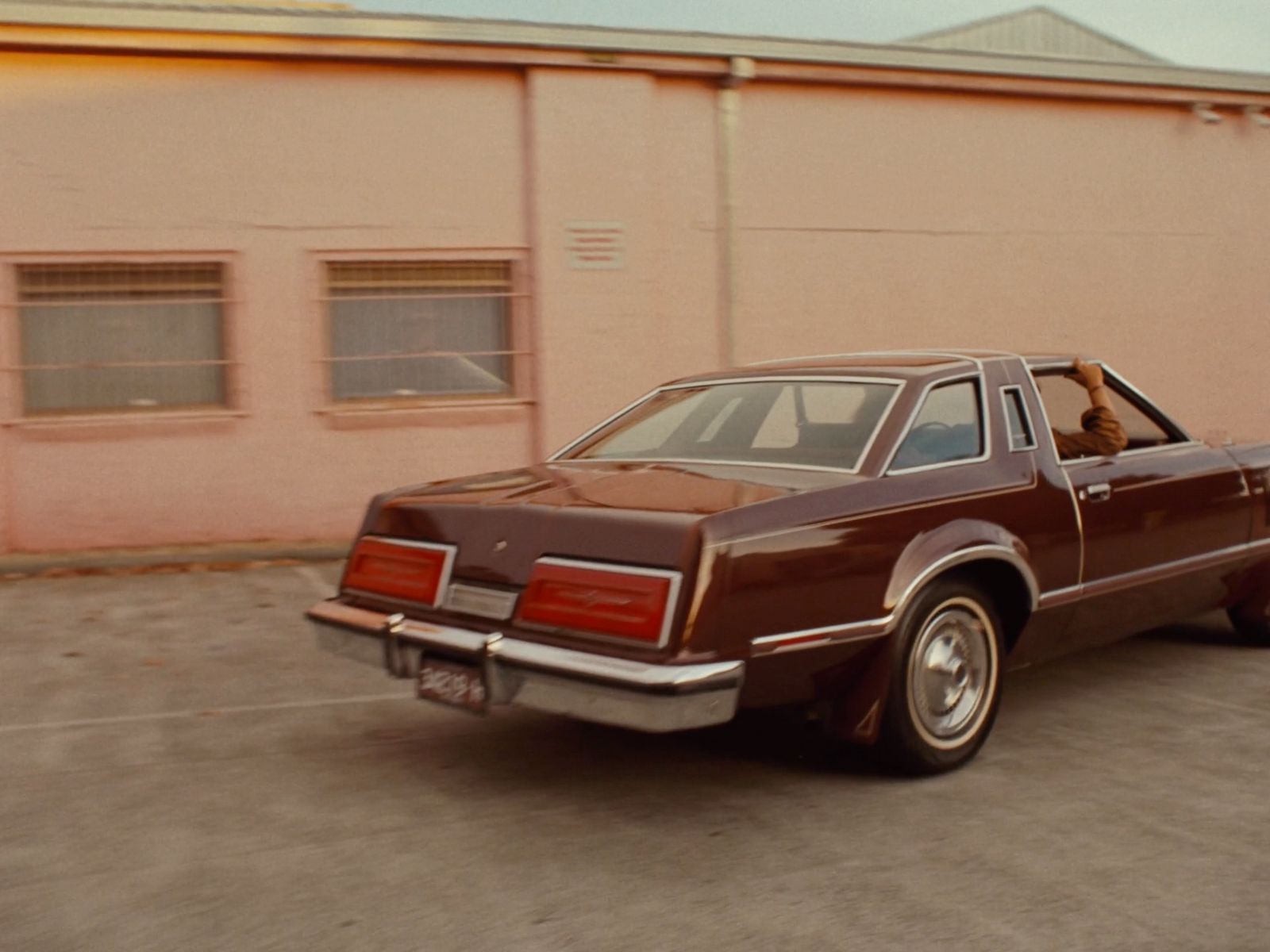 a brown car parked in front of a pink building