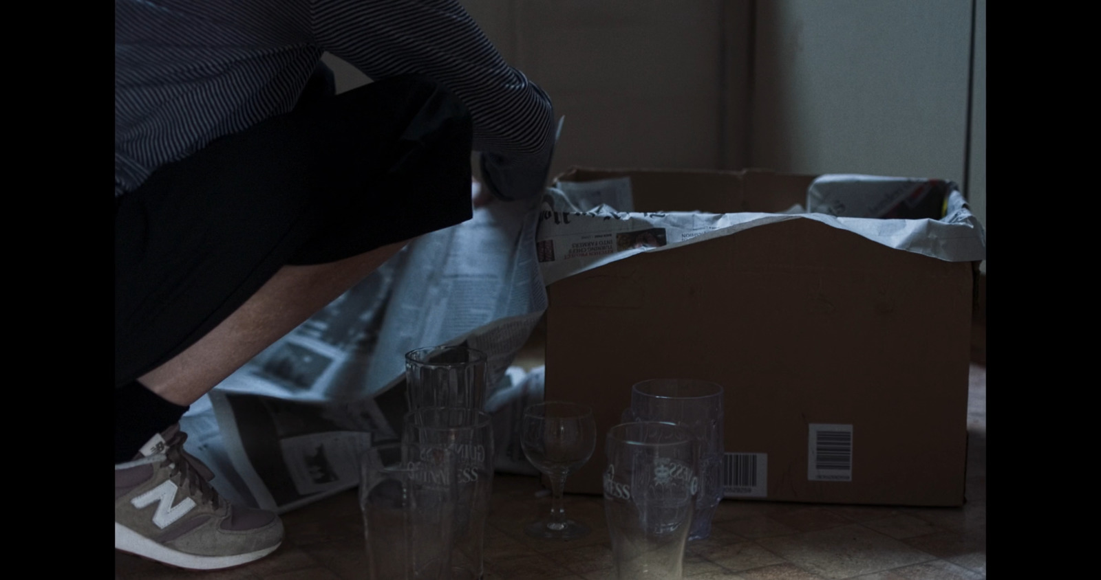 a man bending over a box filled with empty glasses