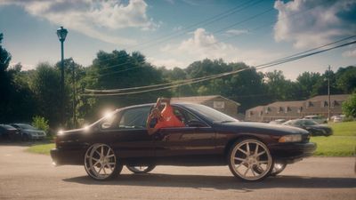 a woman sitting in the driver's seat of a black car