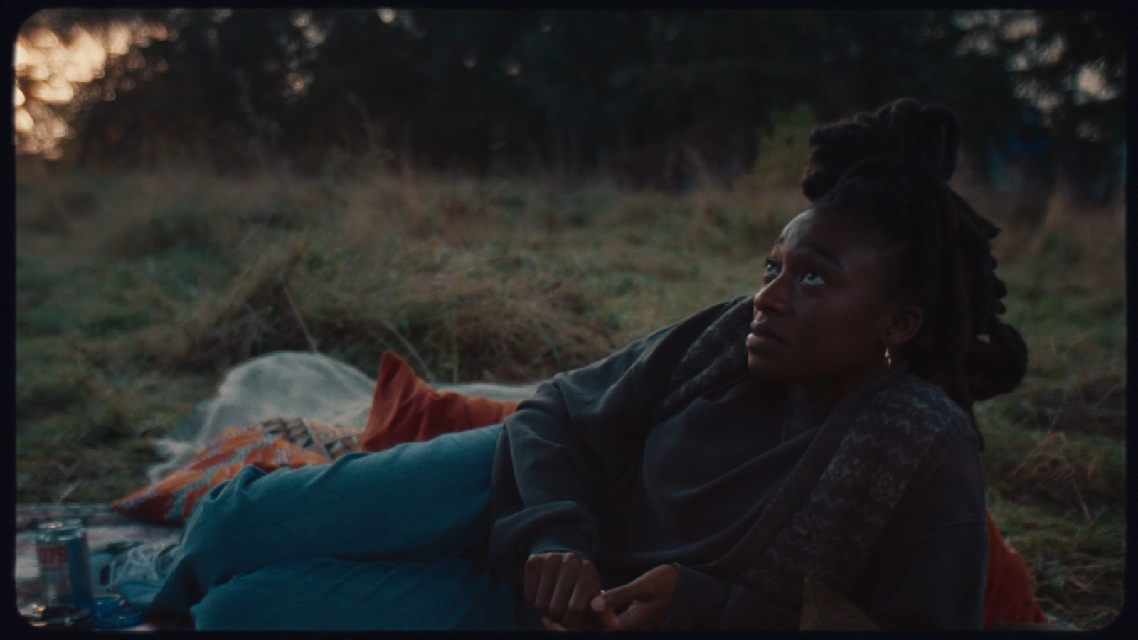 a woman sitting on a blanket in a field