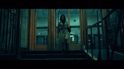 a woman in a trench coat walking down a set of stairs