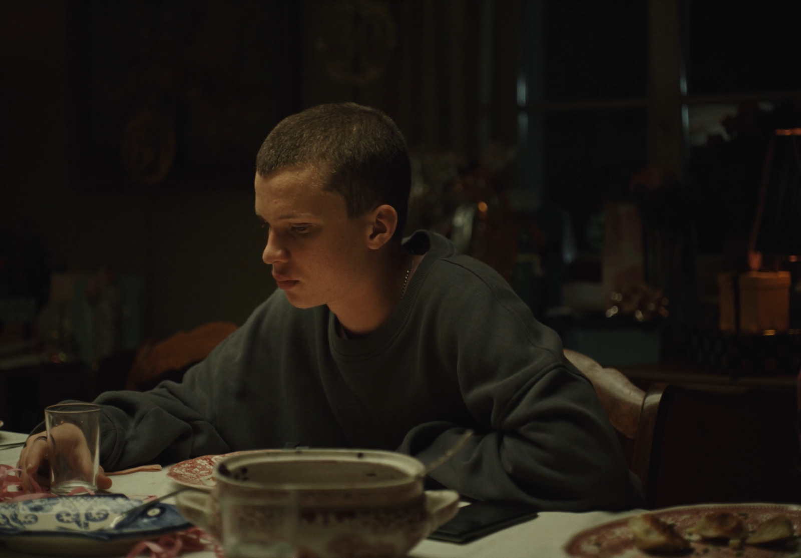 a boy sitting at a table with a plate of food