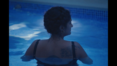 a woman sitting in a pool with a tattoo on her back