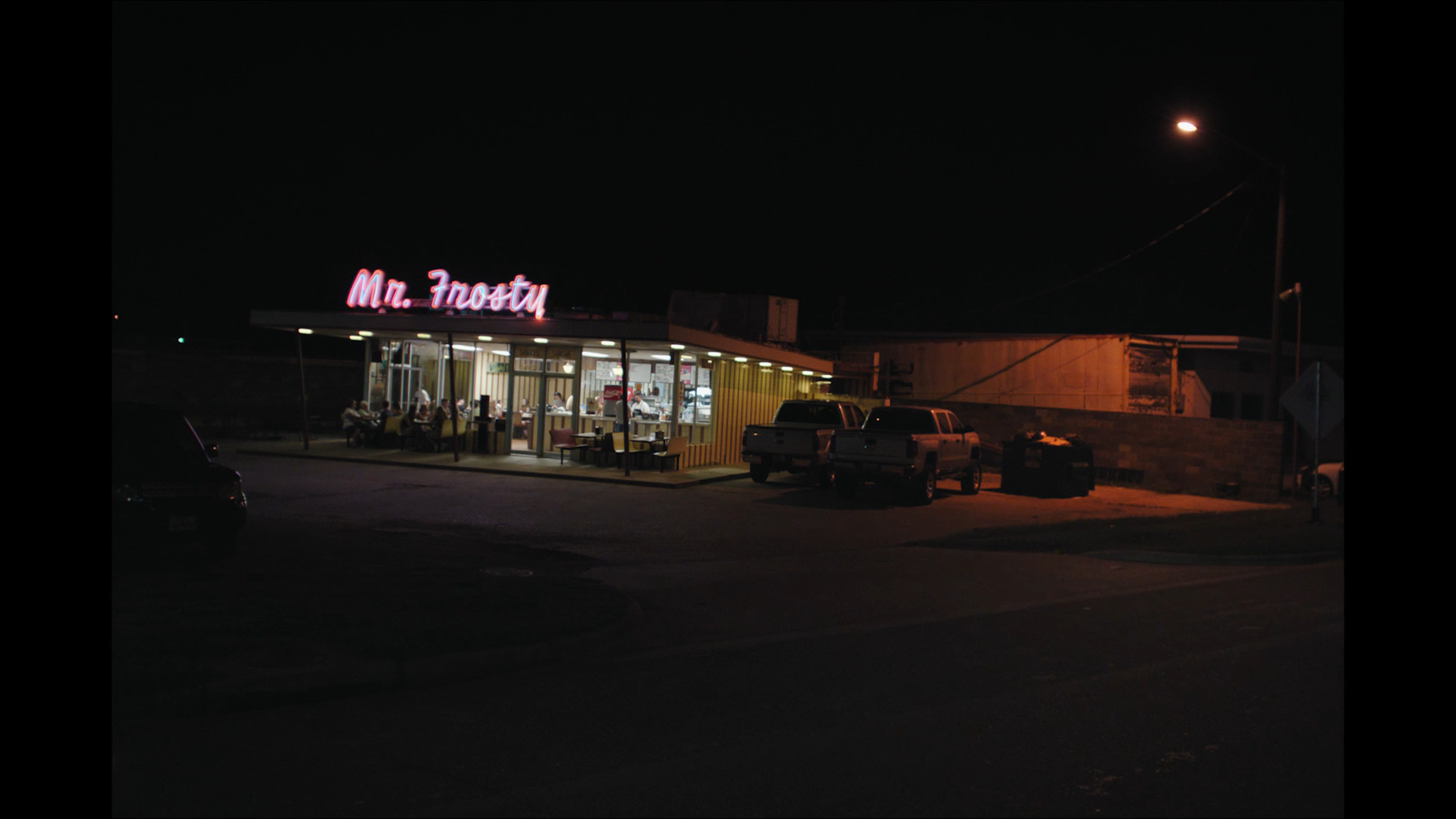 a gas station at night with a neon sign