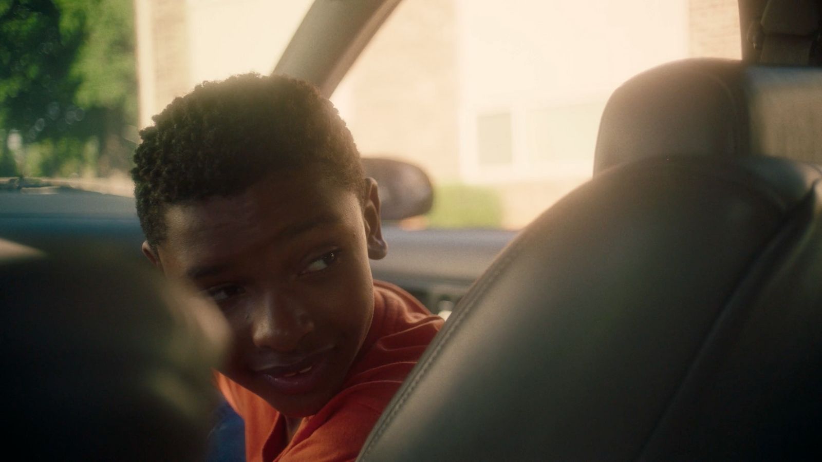 a young man sitting in a car looking at the camera