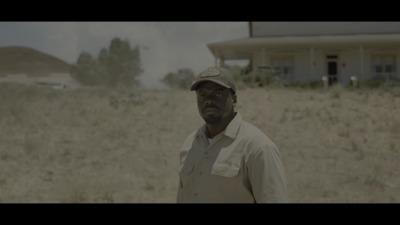 a man standing in a field with a house in the background