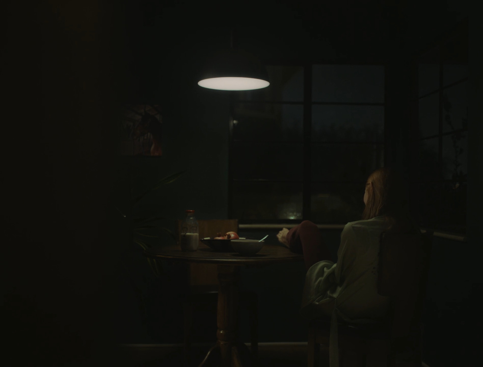 a woman sitting at a table in a dark room