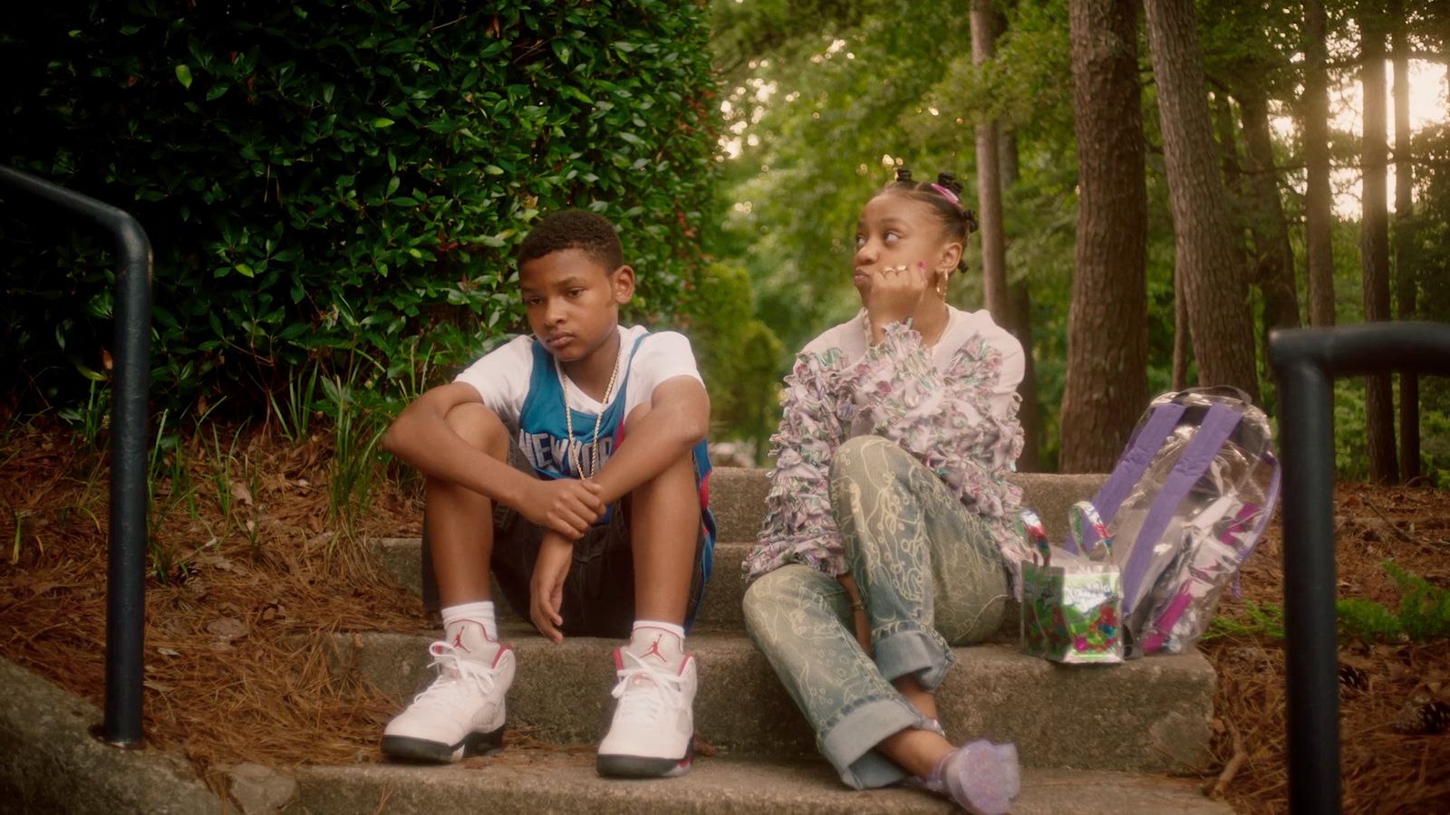 a boy and a girl sitting on steps in the woods