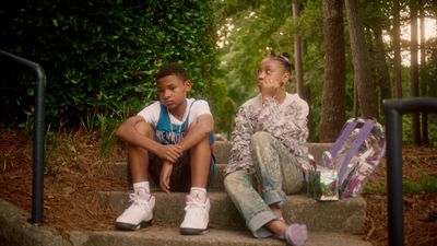 a boy and a girl sitting on steps in the woods