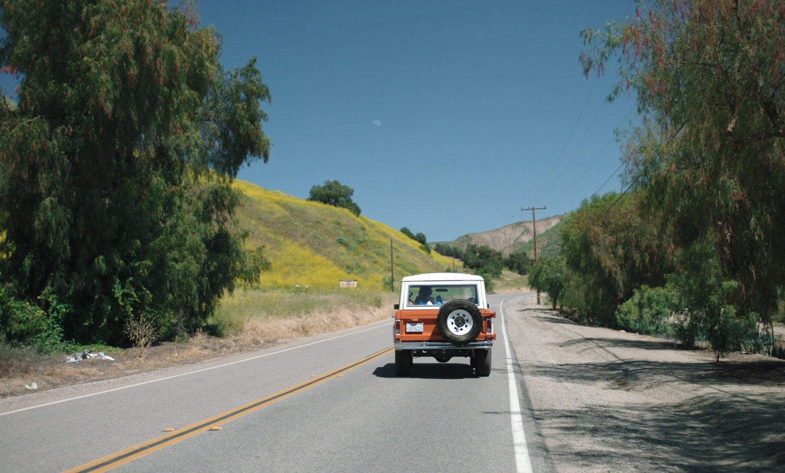 an orange and white jeep driving down a road