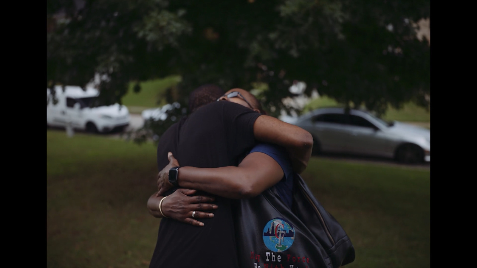 two people hugging each other in a park