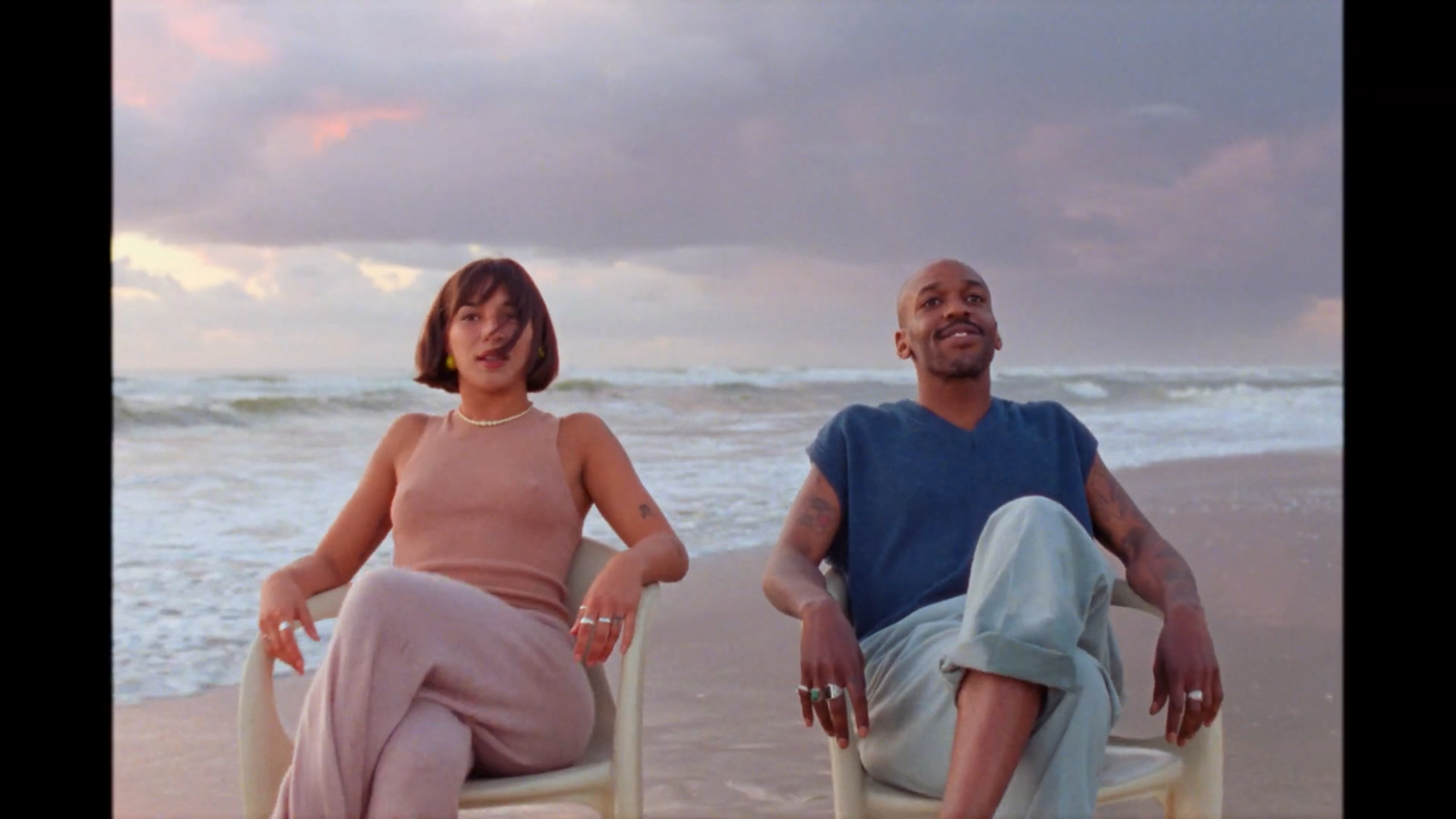 a man and a woman sitting in chairs on the beach