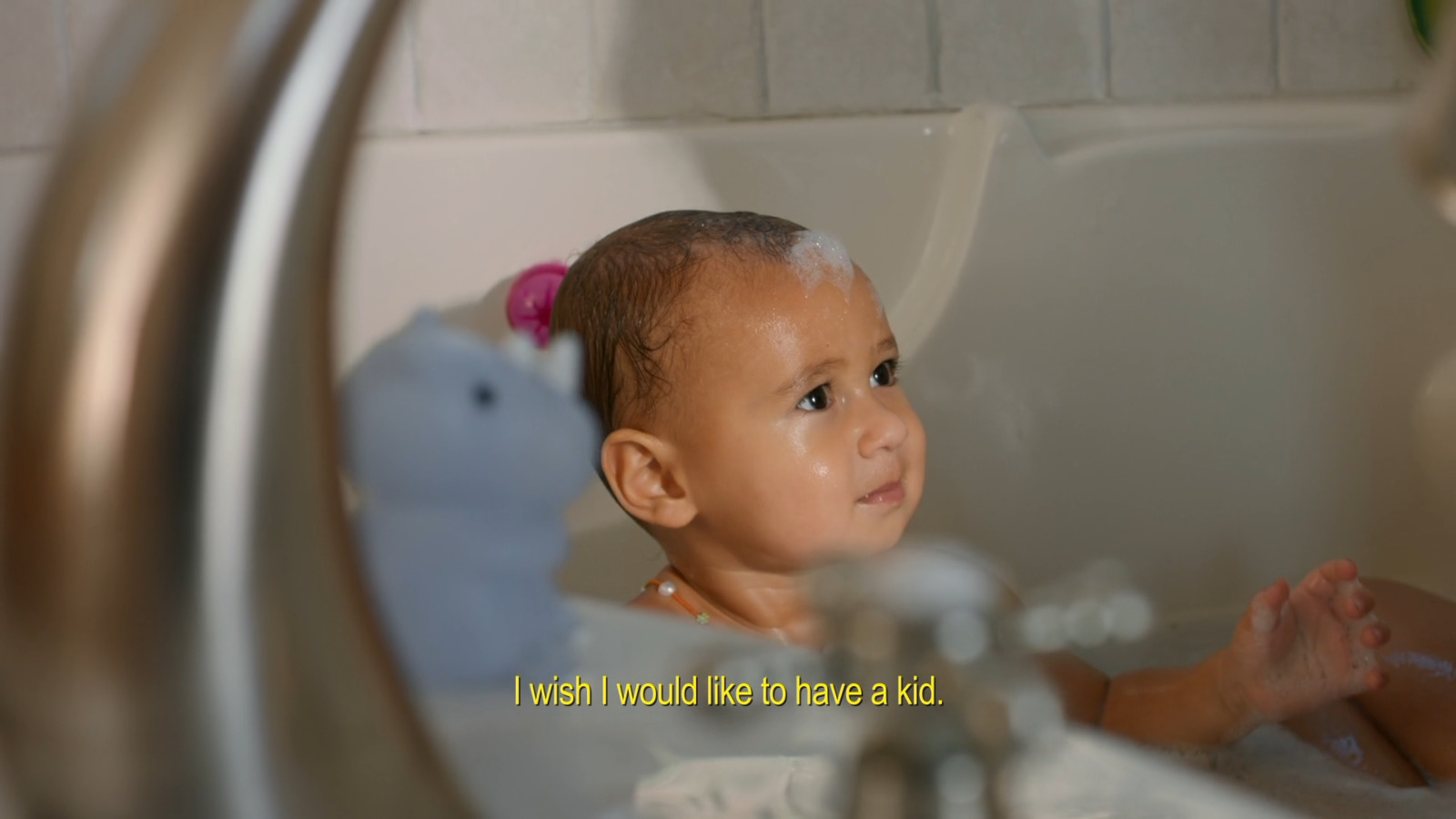 a baby sitting in a bathtub looking at himself in the mirror