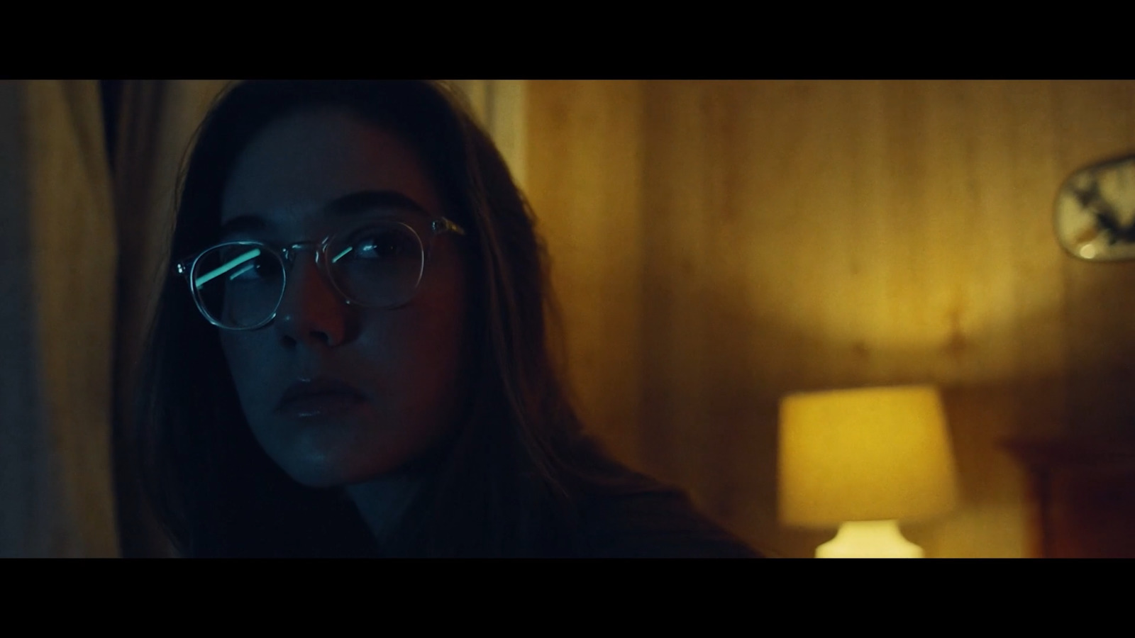 a woman wearing glasses in a dimly lit room