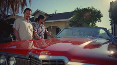 a man and a woman standing next to a red car