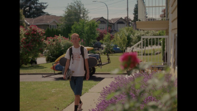 a man walking down a sidewalk next to a flower garden