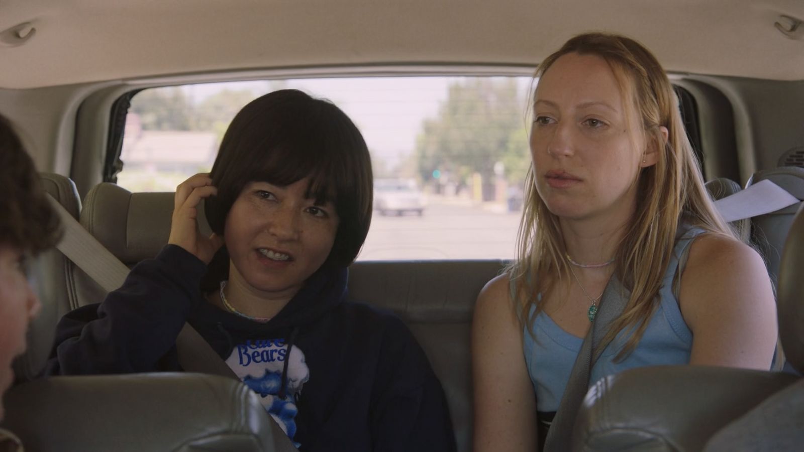 a woman sitting in the back seat of a car talking on a cell phone